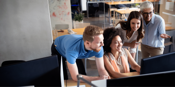 Inclusive team of 4 people collaborating on a desktop computer in a modern office