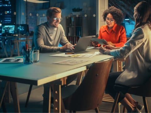 3 employees collaborating together in an empty office at night