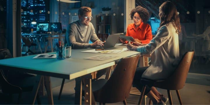 3 employees collaborating together in an empty office at night
