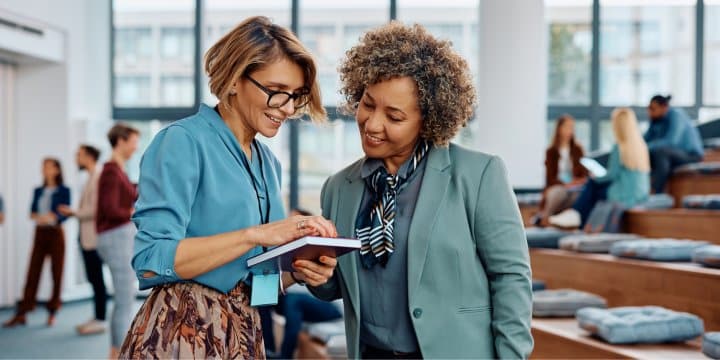 Deux femmes collaborent sur une tablette dans un open space