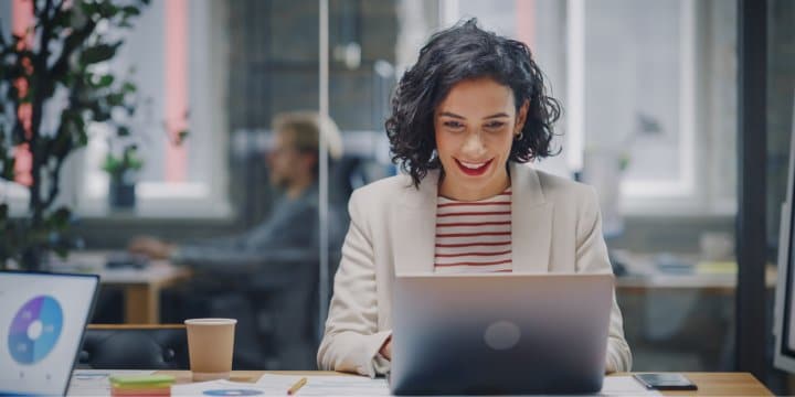 Young woman sitting in a conference room and smiling while looking at her laptop screen
