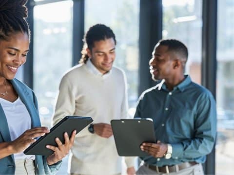 3 people looking at a tablet in a standard office