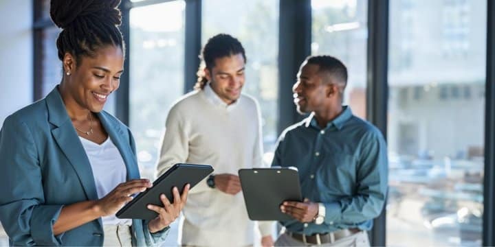 3 people looking at a tablet in a standard office