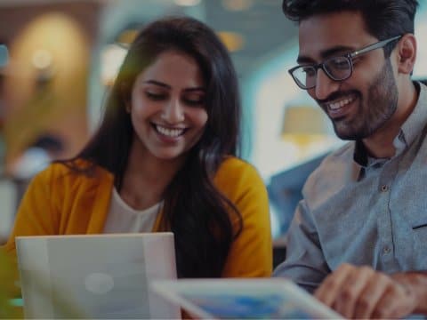 Indian coworkers collaborating on a laptop in a modern work environment