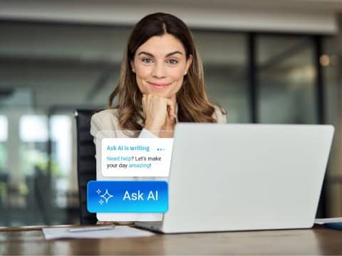 Middle-aged woman posing alone in an office space with a laptop in front of her, out of which Ask AI comes out