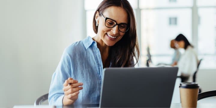 Middle-aged woman smiling while working on her laptop